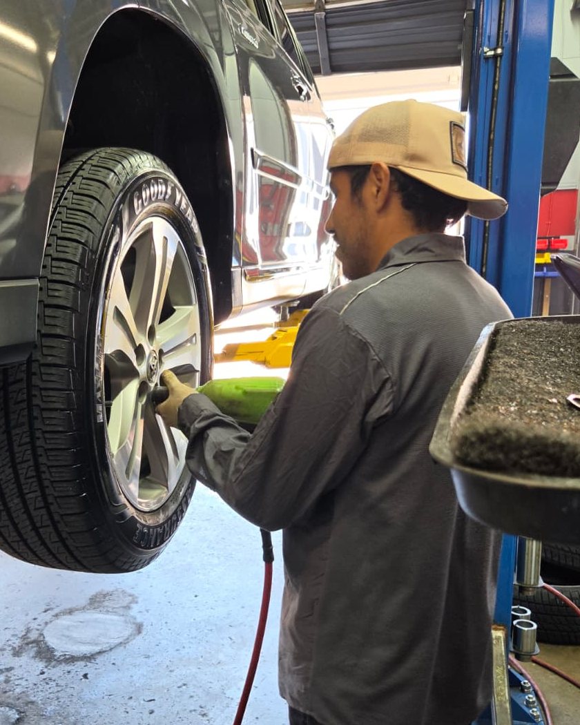 A Frontline technician changing the oil filter on an SUV raised on the lift
