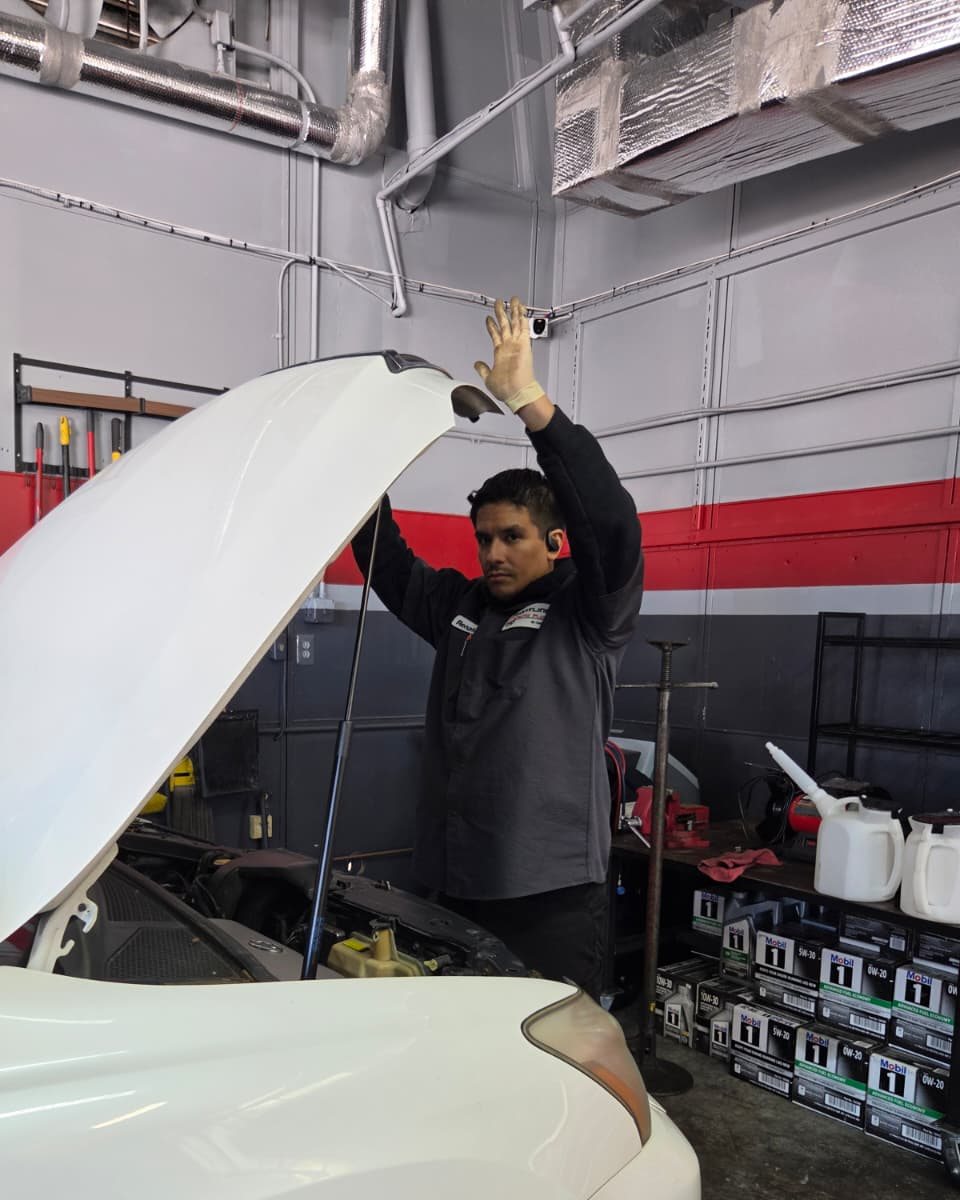 A Frontline technician checking under the hood of a customer car